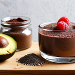 **Image:** A brightly lit kitchen scene. On a wooden countertop, there's a homemade chocolate mousse in a glass bowl, garnished with fresh raspberries and chia seeds. Next to it are ingredients: ripe avocados, cocoa powder, a jar of honey, and a small bowl of chia seeds. Focus on the textures and vibrant colors.